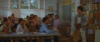 Movie still from “Sounder” (1972), directed by Martin Ritt – A group of children sitting at a table in front of a blackboard; Wide shot, Over the shoulder angle