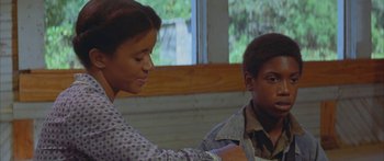 Movie still from “Sounder” (1972), directed by Martin Ritt – A young girl and a young boy sitting next to each other in front of a window; Medium shot, Over the shoulder angle