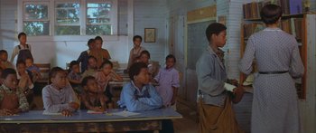 Movie still from “Sounder” (1972), directed by Martin Ritt – A group of people sitting at a table in a room; Wide shot, Over the shoulder angle