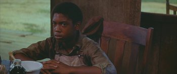 Movie still from “Sounder” (1972), directed by Martin Ritt – A young man sitting on a chair in a room; Close Up shot, High angle