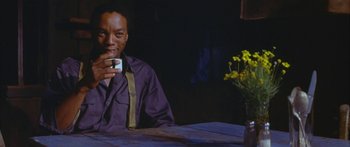 Movie still from “Sounder” (1972), directed by Martin Ritt – A man sitting at a table drinking a cup of coffee; Medium shot, Low angle