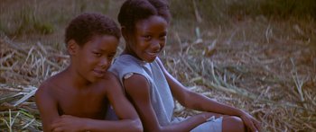 Movie still from “Sounder” (1972), directed by Martin Ritt – Two children sitting on the ground smiling for the camera; Close Up shot, High angle