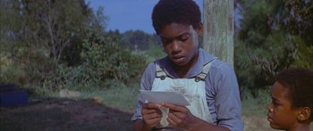 Movie still from “Sounder” (1972), directed by Martin Ritt – A young man reading a piece of paper in front of a tree; Close Up shot, Over the shoulder angle