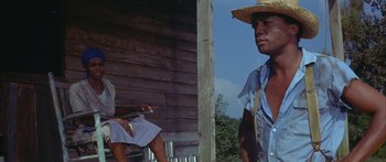 Movie still from “Sounder” (1972), directed by Martin Ritt – A man in a straw hat and a woman in a blue dress; Medium shot, Low angle
