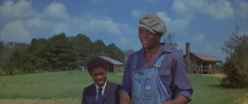 Movie still from “Sounder” (1972), directed by Martin Ritt – A man and a boy standing next to each other in a field; Medium shot, Low angle