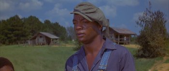 Movie still from “Sounder” (1972), directed by Martin Ritt – An african american man wearing a hat and overalls in a field; Close Up shot, Low angle