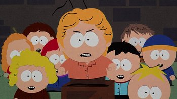 Movie still from “South Park: Bigger, Longer & Uncut” (1999), directed by Trey Parker – A group of people gathered around a cartoon character; Medium shot, Low angle
