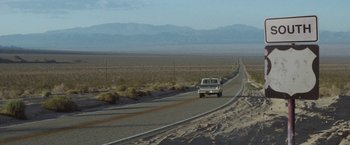 Movie still from “Southbound” (2015), directed by Tyler Gillett – A truck driving down a road in the middle of the desert; Extreme Wide shot, High angle