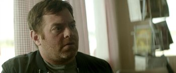 Movie still from “Southbound” (2015), directed by Tyler Gillett – A person sitting in front of a window; Close Up shot, Over the shoulder angle