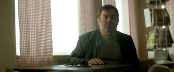 Movie still from “Southbound” (2015), directed by Tyler Gillett – A man sitting at a wooden table with headphones on; Medium shot, Over the shoulder angle