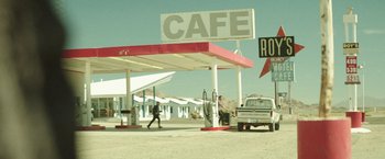 Movie still from “Southbound” (2015), directed by Tyler Gillett – A man walking down a street near a gas station; Extreme Wide shot, Over the shoulder angle