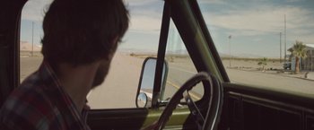 Movie still from “Southbound” (2015), directed by Tyler Gillett – A man driving a car on the side of the road; Wide shot, Over the shoulder angle