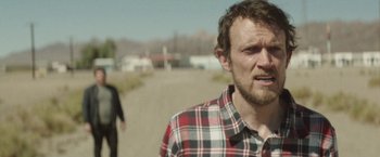 Movie still from “Southbound” (2015), directed by Tyler Gillett – A man standing on the side of a road with his mouth wide open; Close Up shot, Over the shoulder angle