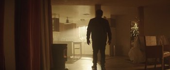 Movie still from “Southbound” (2015), directed by Tyler Gillett – A man standing in a kitchen in the dark; Wide shot, Low angle