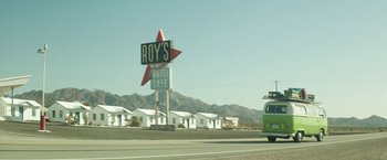 Movie still from “Southbound” (2015), directed by Tyler Gillett – A car driving down a street next to a motel sign; Extreme Wide shot, Low angle