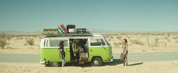Movie still from “Southbound” (2015), directed by Tyler Gillett – A group of people standing in front of a green van; Wide shot, Low angle