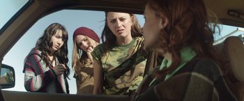Movie still from “Southbound” (2015), directed by Tyler Gillett – A group of young women standing next to each other in a car; Medium shot, Over the shoulder angle