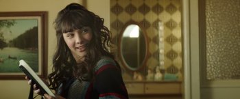 Movie still from “Southbound” (2015), directed by Tyler Gillett – A woman with long brown curly hair smiles for the camera; Close Up shot, Over the shoulder angle