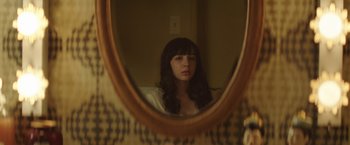 Movie still from “Southbound” (2015), directed by Tyler Gillett – A woman looking at herself in a mirror; Close Up shot, Over the shoulder angle