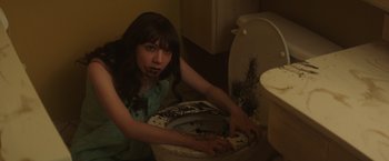 Movie still from “Southbound” (2015), directed by Tyler Gillett – A woman is sitting on a toilet in a bathroom; Close Up shot, High angle