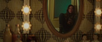 Movie still from “Southbound” (2015), directed by Tyler Gillett – A woman sitting in front of a mirror holding a cell phone; Medium shot, Overhead angle