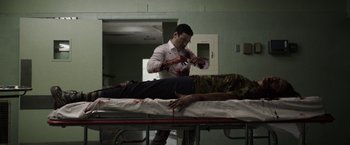 Movie still from “Southbound” (2015), directed by Tyler Gillett – A man in white shirt standing next to a dead body; Medium shot, Low angle