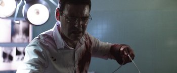 Movie still from “Southbound” (2015), directed by Tyler Gillett – A man with blood on his shirt and glasses is playing a video game; Close Up shot, Low angle