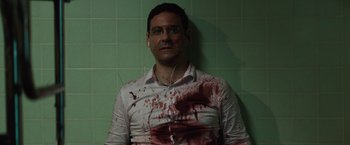 Movie still from “Southbound” (2015), directed by Tyler Gillett – A man in a white shirt with blood all over his face; Medium shot, High angle