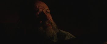 Movie still from “Southbound” (2015), directed by Tyler Gillett – A man with a long beard is looking at the camera; Close Up shot, Over the shoulder angle