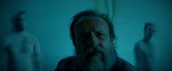 Movie still from “Southbound” (2015), directed by Tyler Gillett – A man with a long beard is looking at the camera; Close Up shot, Overhead angle