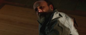 Movie still from “Southbound” (2015), directed by Tyler Gillett – A man with a beard and a jacket on looking at the camera; Close Up shot, Low angle