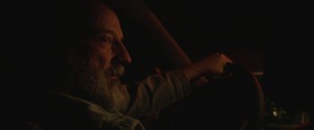 Movie still from “Southbound” (2015), directed by Tyler Gillett – An older man sitting in a car in the dark; Close Up shot, Over the shoulder angle
