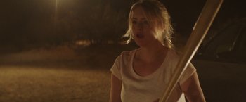 Movie still from “Southbound” (2015), directed by Tyler Gillett – A woman standing in a field at night holding a baseball bat; Close Up shot, Over the shoulder angle