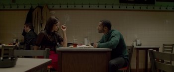 Movie still from “Sparkle” (2012), directed by Salim Akil – A man and a woman sitting at a table smoking; Medium shot, Over the shoulder angle
