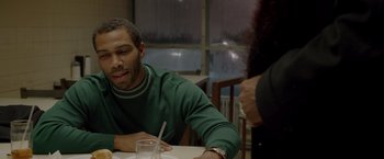 Movie still from “Sparkle” (2012), directed by Salim Akil – A man sitting at a table in front of a glass of water; Medium shot, Over the shoulder angle
