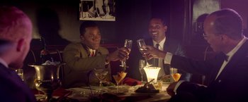 Movie still from “Sparkle” (2012), directed by Salim Akil – A group of people sitting at a table with wine glasses; Medium shot, High angle