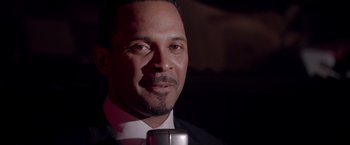 Movie still from “Sparkle” (2012), directed by Salim Akil – A person wearing a suit holding a microphone; Close Up shot, Low angle