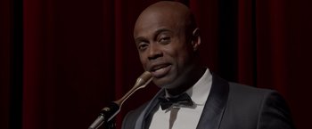Movie still from “Sparkle” (2012), directed by Salim Akil – A man in a suit and tie holding a microphone up to his mouth; Close Up shot, Low angle
