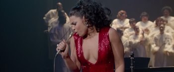 Movie still from “Sparkle” (2012), directed by Salim Akil – A woman in a red dress singing into a microphone; Medium shot, Overhead angle