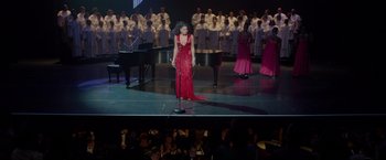Movie still from “Sparkle” (2012), directed by Salim Akil – A woman in a red dress singing in front of an audience; Extreme Wide shot, High angle