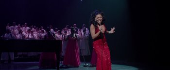 Movie still from “Sparkle” (2012), directed by Salim Akil – A woman in a red dress singing into a microphone; Medium shot, High angle