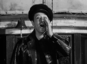 Movie still from “Spawn of the North” (1938), directed by Henry Hathaway – A man wearing a hat and a leather jacket is holding his hand to his mouth; Medium shot, Low angle