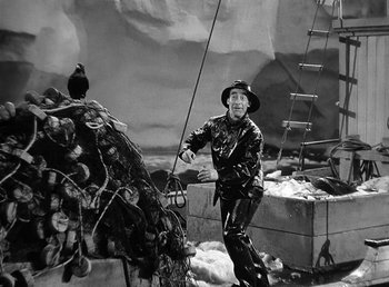Movie still from “Spawn of the North” (1938), directed by Henry Hathaway – A man holding a fishing pole next to a bird on a pole; Wide shot, High angle