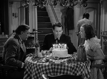 Movie still from “Spawn of the North” (1938), directed by Henry Hathaway – A man sitting at a table in front of a birthday cake; Medium shot, High angle