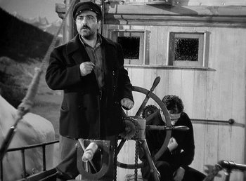 Movie still from “Spawn of the North” (1938), directed by Henry Hathaway – A black and white photo of a man and a woman in front of a steering wheel; Medium shot, Low angle