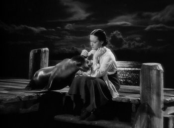 Movie still from “Spawn of the North” (1938), directed by Henry Hathaway – A black and white photo of a woman petting a seal; Wide shot, High angle