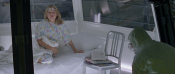 Movie still from “Species” (1995), directed by Roger Donaldson – A young girl sitting on a bed next to a chair; Medium shot, High angle