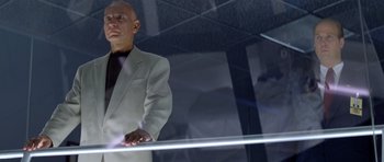 Movie still from “Species” (1995), directed by Roger Donaldson – A man in a white suit standing in front of a mirror; Medium shot, Low angle