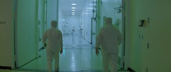 Movie still from “Species” (1995), directed by Roger Donaldson – A group of people in white suits in a room; Extreme Wide shot, High angle