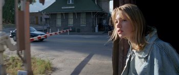 Movie still from “Species” (1995), directed by Roger Donaldson – A woman standing in front of a train station; Close Up shot, Low angle